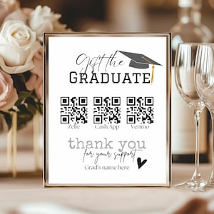 May include: A framed sign with the text "Gift the Graduate" and "thank you for your support." It includes QR codes for Zelle, Cash App, and Venmo, along with a graduation cap graphic. The sign is in a gold frame.