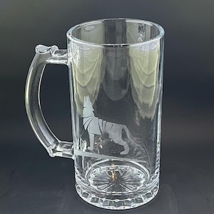 May include: A clear glass beer stein with a handle. The stein features an etched design of a wolf howling at the moon.