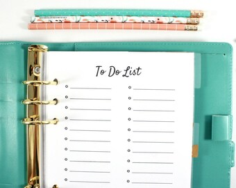 May include: A teal binder with gold rings and a "To Do List" page. The page has lines and circles for checkmarks. Pencils and decorative paper clips in pink, teal, and gold are also visible. A sticker with floral accents is in the corner.