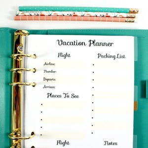 May include: A teal binder with gold rings and a "Vacation Planner" page. The planner includes sections for flight details, packing lists, and places to see. Decorative pencils and paper clips are scattered around the planner.