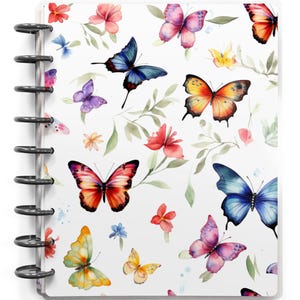 May include: A white notebook with a black spiral binding. The cover is decorated with a watercolor pattern of colorful butterflies, flowers, and green leaves. The butterflies are in shades of blue, orange, pink, and yellow.