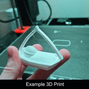 Puede incluir: Una figura blanca impresa en 3D que representa a un peque&ntilde;o personaje acostado en una cuna con un marco de dosel arqueado. El objeto tiene un acabado mate y liso, construido en una sola pieza con l&iacute;neas de capa visibles del proceso.