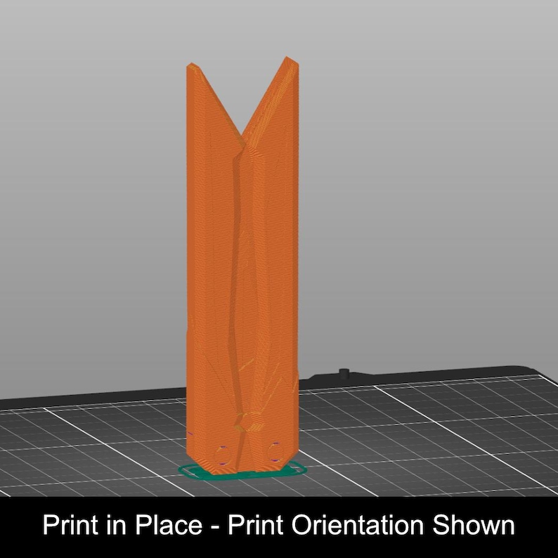 May include: A tall, orange, 3D-printed object with a vertical, elongated shape and a V-shaped top opening. The object stands upright on a dark grid platform. The text "Print in Place - Print Orientation Shown" is displayed at the bottom.
