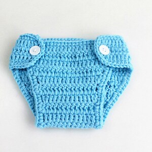 May include: A light blue crocheted diaper with two white buttons.