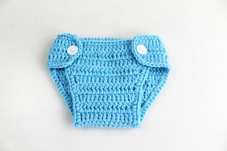 May include: A light blue crocheted diaper with two white buttons.