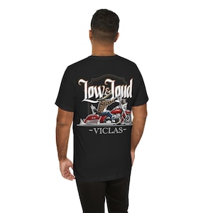 Black t-shirt with a design of a skeleton biker wearing a sombrero riding a red motorcycle with ape hangers, spoke wheels, chrome engine and fishtail pipes. "Low & Loud" text on the top and "Viclas" text on the bottom.