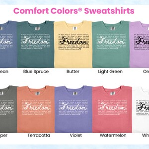 May include: A collection of Comfort Colors sweatshirts in various colors, including blue jean, blue spruce, butter, light green, orchid, pepper, terracotta, violet, watermelon, and white. Each shirt features the word "Freedom" and text.