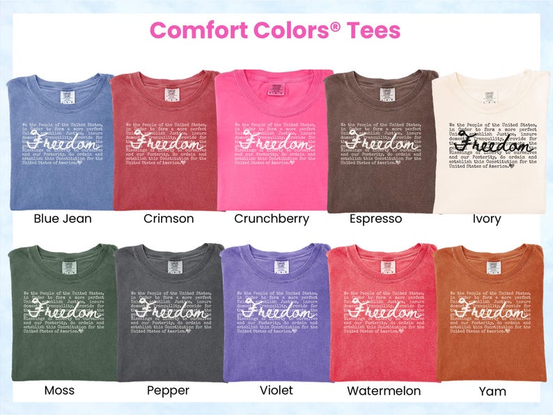 May include: A display of Comfort Colors tees in various colors, including blue jean, crimson, and ivory. Each shirt features the word "Freedom" in a cursive font, along with a quote. The shirts are arranged in rows, showcasing the range of available colors.