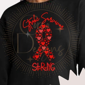 Peut inclure: Sweat-shirt noir avec un design de ruban rouge et le texte "Stroke Survivor" dans un cercle doré. Le ruban est composé de cœurs rouges.