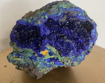 May include: A large, blue and green mineral specimen with a rough, textured surface. The mineral has a large, open cavity filled with sparkling blue crystals.