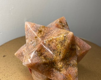 May include: A pink and brown star-shaped stone sculpture with a smooth, polished finish.