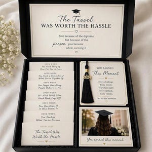 May include: A black gift box containing graduation-themed items, including a card with the text The Tassel Was Worth The Hassle, seven Open When envelopes, a black 2024 graduation tassel, and a photo card of a graduate in a cap and gown.