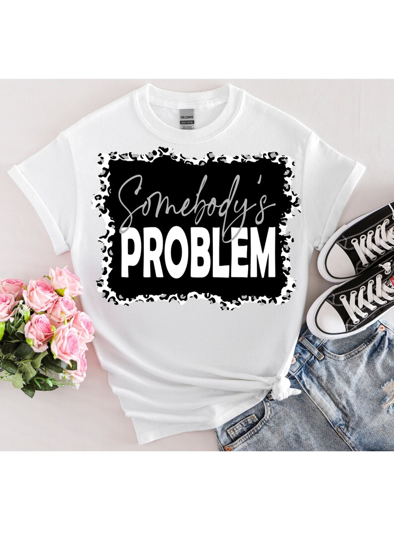 May include: White t-shirt with a black and white leopard print graphic that says "Somebody's Problem" in white text.