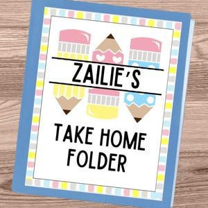 May include: A blue folder with a white cover featuring the text "ZAILIE'S TAKE HOME FOLDER." The cover design includes three colorful pencil illustrations in pink, yellow, and blue. The folder has a light blue border and is set against a wooden background.