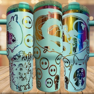 May include: Three light blue insulated tumblers with various anime-style character designs. Each tumbler features a handle, a clear lid, and a metallic, iridescent interior. The designs include a dragon, a rabbit-like creature, and other characters.