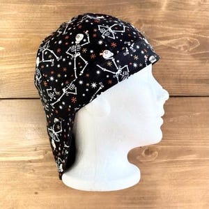 May include: Black welding cap with a skull and crossbones pattern. The cap has a flap that can be worn down to protect the neck.