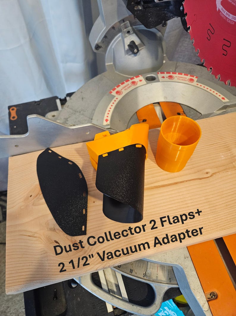 K&ouml;nnte beinhalten: Ein Set von Holzbearbeitungszubeh&ouml;r, darunter eine schwarze Staubabdeckklappe, ein gelb-schwarzer Staubabscheider und ein orangefarbener Staubsaugeradapter. Der Text "Dust Collector 2 Flaps+ 2 1/2" Vacuum Adapter" ist auf der Holzoberfl&auml;che aufgedruckt.