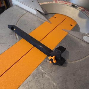 May include: A black and orange miter saw with a black handle and an orange knob. The saw has a silver blade and an orange base. The saw is designed for cutting wood and other materials.