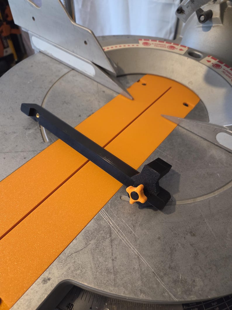 May include: A black and orange miter saw with a black handle and an orange knob. The saw has a silver blade and an orange base. The saw is designed for cutting wood and other materials.