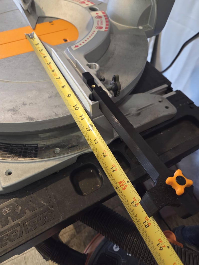 May include: A miter saw with a yellow measuring tape extended across the blade. The saw is gray and black with an orange accent. The tape shows measurements up to 19 inches.