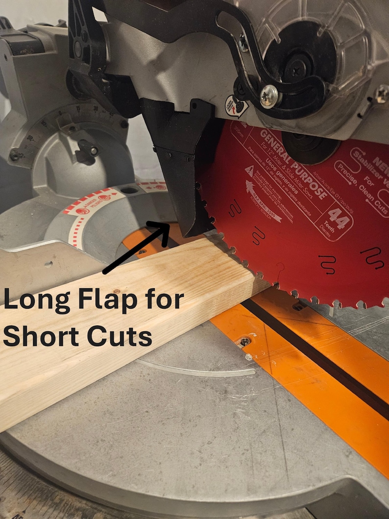 K&ouml;nnte beinhalten: Eine Gehrungss&auml;ge mit einem roten S&auml;geblatt schneidet ein Holzst&uuml;ck. Der Text "Long Flap for Short Cuts" ist sichtbar. Das S&auml;geblatt hat 44 Z&auml;hne und ist f&uuml;r pr&auml;zise, saubere Schnitte ausgelegt. F&uuml;r 12" Gehrungs- und Schiebemeters&auml;gen.