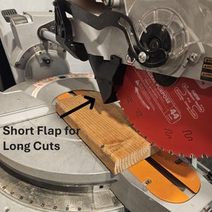 K&ouml;nnte beinhalten: Nahaufnahme einer Gehrungss&auml;ge mit einem Holzbrett zum Schneiden. Das S&auml;geblatt ist rot, und der Text "Short Flap for Long Cuts" ist sichtbar. Die S&auml;ge ist f&uuml;r pr&auml;zise Schnitte konzipiert.