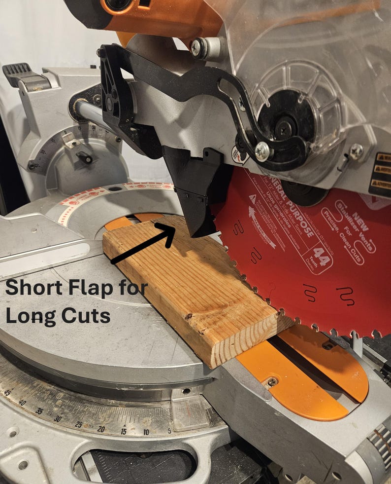 K&ouml;nnte beinhalten: Nahaufnahme einer Gehrungss&auml;ge mit einem Holzbrett zum Schneiden. Das S&auml;geblatt ist rot, und der Text "Short Flap for Long Cuts" ist sichtbar. Die S&auml;ge ist f&uuml;r pr&auml;zise Schnitte konzipiert.