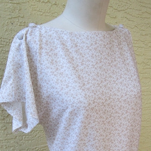 May include: A white dress with a brown floral pattern and short sleeves. The dress has a scoop neckline and a gathered skirt.