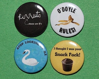 May include: Four round button badges with different designs. The first badge is black with white text that says "Pirruto...those are Z's". The second badge is white with black text that says "O'Doyle Rules!" and a banana peel. The third badge is blue with white text that says "Stop Looking...At Me" and a white swan. The fourth badge is yellow with black text that says "I thought I was your Snack Pack!" and a brown chocolate pudding cup.