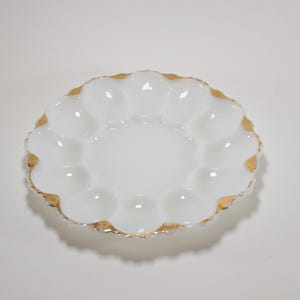 Peut inclure: Plat à œufs en verre laiteux blanc avec un bord doré. La plaque comporte 6 sections pour contenir des œufs.