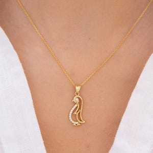 May include: A gold chain necklace with a small, detailed penguin pendant. The pendant is adorned with small, clear stones.