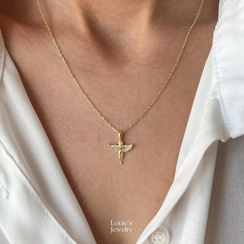 Pu&ograve; includere: Una collana con catena dorata con un piccolo ciondolo a forma di angelo decorato con pietre di zircone cubico trasparenti. Il ciondolo &egrave; dettagliato con un design testurizzato.