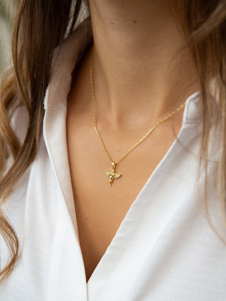 Pu&ograve; includere: Una collana con catena dorata con un piccolo ciondolo a forma di angelo con accenti di cristallo trasparente.