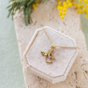 May include: A gold angel pendant necklace with a heart detail, displayed in a white velvet box.