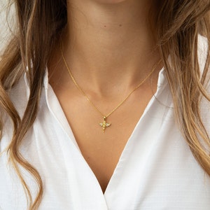 Pu&ograve; includere: Una collana con catena dorata con un piccolo ciondolo a forma di angelo con pietre di zircone cubico trasparenti.
