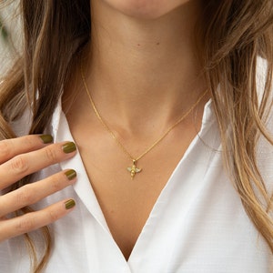 Pu&ograve; includere: Una collana con catena d'oro con un piccolo ciondolo a forma di angelo. L'angelo ha le ali e un'aureola.