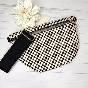 May include: A black and white checkered fanny pack with a black adjustable strap and a gold zipper.