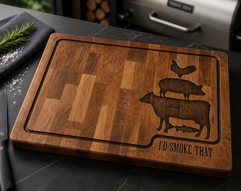 Puede incluir: Tabla de cortar rectangular de madera con una ranura para jugos tallada. La tabla presenta un diseño de una vaca, un cerdo y un pollo apilados uno encima del otro, con el texto "I'D SMOKE THAT".