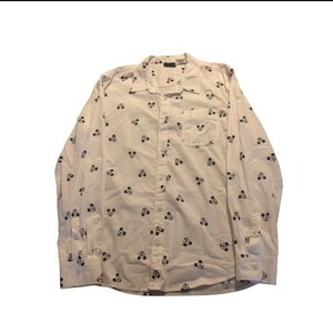 May include: A long-sleeve button-down shirt in off-white featuring a repeating black pattern of Mickey Mouse heads. The shirt includes a standard collar, a single chest pocket on the left side, and buttoned cuffs on the long sleeves.