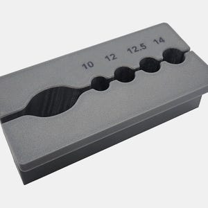 May include: Gray plastic tool with five holes for sizing rings. The holes are labeled 10, 12, 12.5, and 14.
