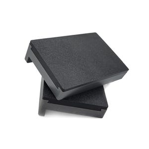 May include: Two black rectangular exercise platforms stacked on top of each other. The platforms are made of a textured material.