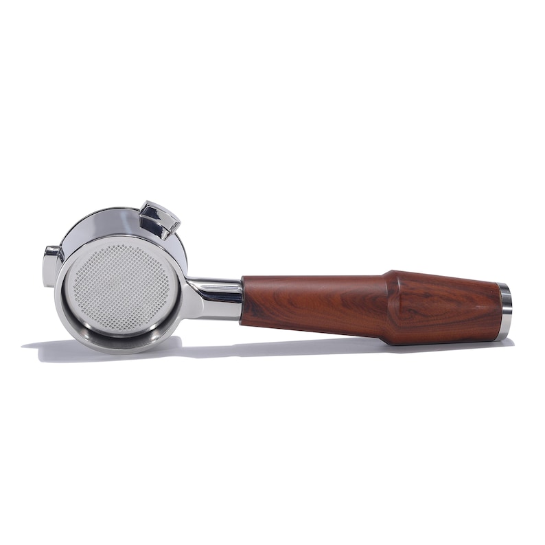 May include: A stainless steel espresso portafilter with a wooden handle. The portafilter has a single spout and a mesh filter basket.
