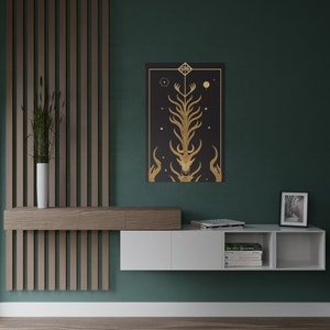 K&ouml;nnte beinhalten: Ein wei&szlig;es, schwebendes Regal mit drei F&auml;chern. Das Regal ist an einer gr&uuml;nen Wand montiert. Das Regal ist mit B&uuml;chern, einem gerahmten Foto und einem schwarzen und goldenen Druck eines stilisierten Baumes mit einem Hirschsch&auml;del an der Basis dekoriert.