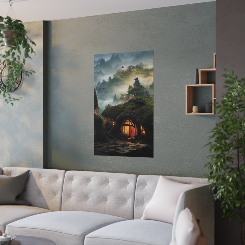 May include: A vertical poster featuring a fantasy landscape with hobbit-style homes nestled into a hillside. The artwork depicts a village with glowing windows, a winding stone path, and misty mountains in the background. The color palette is dominated by greens, browns, and blues.
