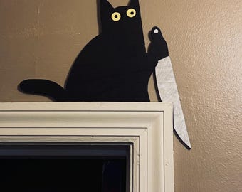 Gato asesino sentado en la puerta o estante de Halloween