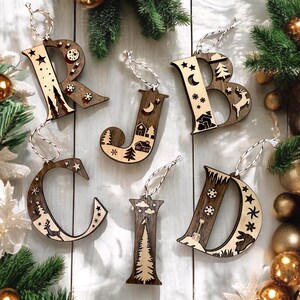 May include: Wooden Christmas decorations shaped like the letters R, J, B, C, I, and D. Each letter is decorated with a winter scene, including trees, houses, stars, and a deer.