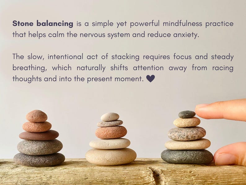 May include: Three stacks of smooth, rounded river stones in shades of gray, tan, and reddish-brown. The text reads: Stone balancing is a simple yet powerful mindfulness practice that helps calm the nervous system and reduce anxiety. The slow, intentional act of stacking requires focus and steady breathing, which naturally shifts attention away from racing thoughts and into the present moment.