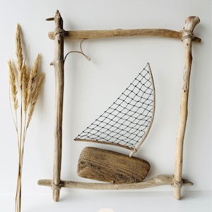 May include: A driftwood sailboat with a black net sail and a wooden base is framed by a rustic wooden structure. Dried wheat stalks are on the left. The number 9 is in a white square at the bottom.