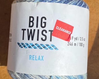 Puede incluir: Ovillo de hilo Big Twist en tonos azules y blancos. La etiqueta dice "BIG TWIST" y "RELAX" en azul. Una pegatina roja de "CLEARANCE" es visible. El hilo es de 246 m / 100 g.