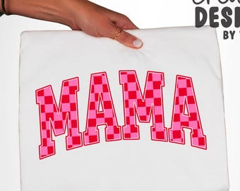 Peut inclure: Un t-shirt blanc avec le mot MAMA imprimé dans une grande police de style universitaire arquée. Les lettres présentent un motif à carreaux rouge et rose avec un fin contour rouge. Le texte creative DESIGNS BY TSC figure en haut à droite.